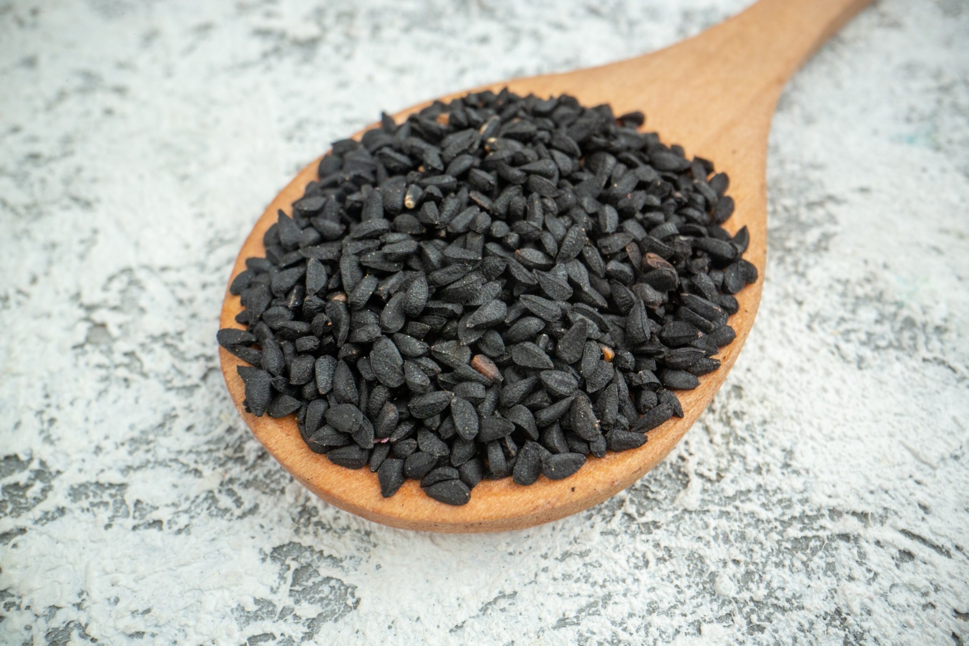 bottom-view-black-cumin-seeds-wooden-spoon-grey (1) (1) (1)